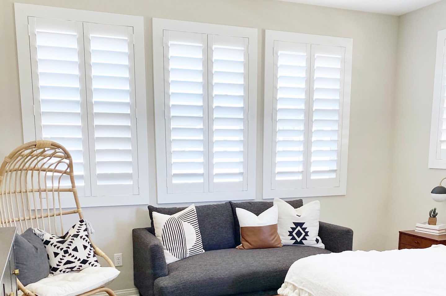 white Polywood shutters on windows in a stylish bedroom