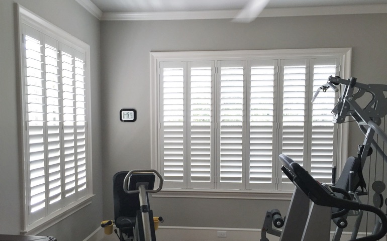 Weatherstripping window treatments are especially important in rooms with windows on multiple walls. Destin exercise room with shuttered windows.