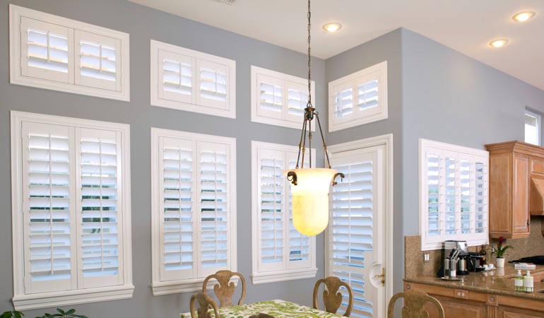 Plantation shutters can resolve both sun glare and energy efficiency problems. White plantation shutters in dining room