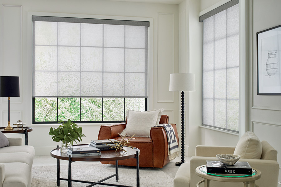 Sheer shades add character and style to your living room. Light gray sheer shades on two large tall windows with a beige and tan styled living room.